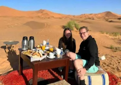 two people sitting at a table in the desert at Luxury Sahara Gold Camp in Merzouga