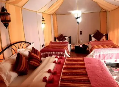 a room with three beds with red flowers on them at Luxury Sahara Gold Camp in Merzouga