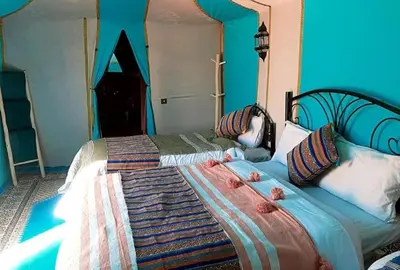 a bedroom with two beds with blue walls at Luxury Sahara Gold Camp in Merzouga