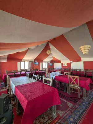 a room with red and white walls and tables and chairs at Air Conditioning Berber Desert Camp in Merzouga