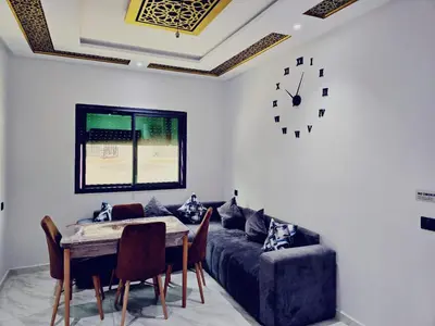 a living room with a couch and a table and a clock at IM Location Euromed Fès in Fès