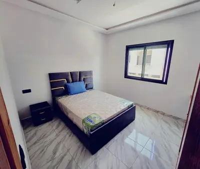 a bedroom with a bed with blue pillows and a window at IM Location Euromed Fès in Fès