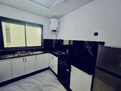 a kitchen with black and white appliances and a window at IM Location Euromed Fès in Fès