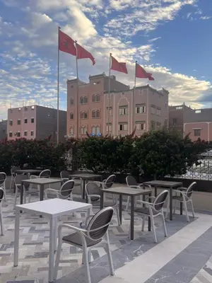 a row of tables and chairs with flags on a roof at Hotel Ourida Zagora in Zagora