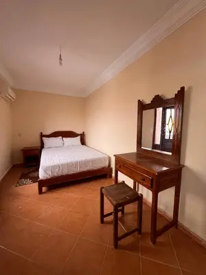 a bedroom with a bed and a table and a mirror at Hotel Ourida Zagora in Zagora