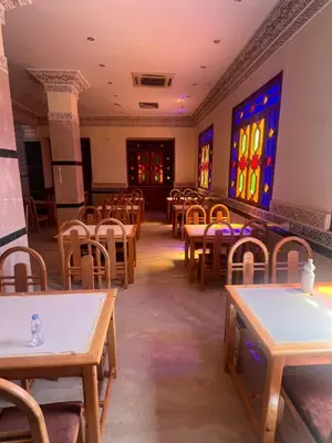 a dining room with tables and stained glass windows at Hotel Ourida Zagora in Zagora