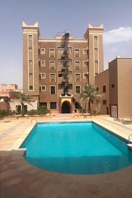 a swimming pool in front of a large building at Hotel Ourida Zagora in Zagora