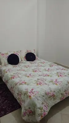 a bed with a floral comforter with two pillows on it at Reda Ghazalie in Meknès