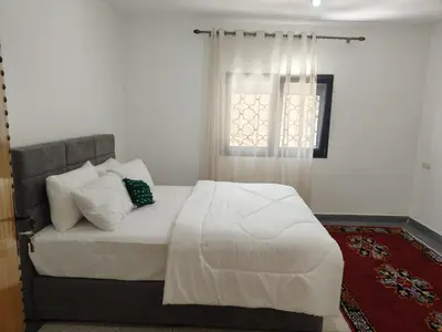 a bedroom with a white bed with a window at Apartement khadija in Azrou