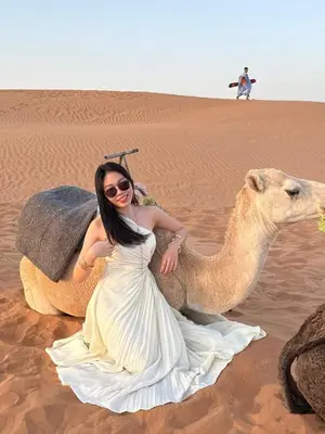 a woman is sitting on a camel in the desert at Kabana Sahara Luxury Camp in Merzouga