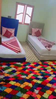 a room with two beds and a colorful rug at Dar Timsal in Tacheddirt