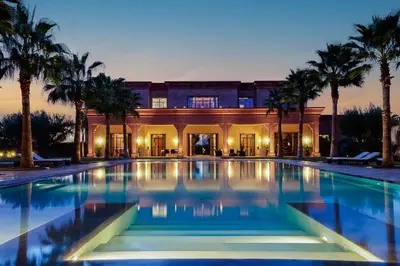 a large swimming pool in front of a house with palm trees at Mexance Villa with large hosting capacity, private heated pool, Fitness and SPA in Oulad Mazoug