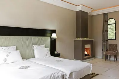 a bedroom with two beds and a fireplace at Mexance Villa with large hosting capacity, private heated pool, Fitness and SPA in Oulad Mazoug
