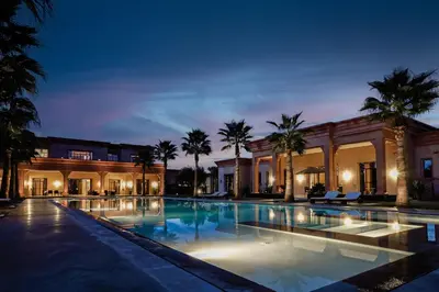 a large swimming pool with palm trees in front of a building at Mexance Villa with large hosting capacity, private heated pool, Fitness and SPA in Oulad Mazoug