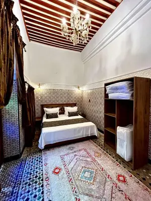 a bedroom with two beds and a chandelier at Dar Al Batoul Meknes in Meknès
