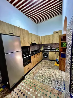 a kitchen with a stainless steel refrigerator and wooden cabinets at Dar Al Batoul Meknes in Meknès