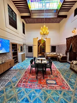 a living room with a table and chairs on a rug at Dar Al Batoul Meknes in Meknès