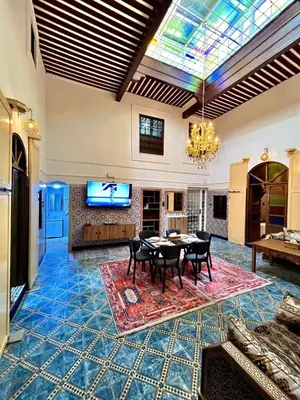 a living room with a table and chairs and a tv at Dar Al Batoul Meknes in Meknès