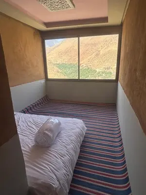 a small bed in a room with a large window at Berber lodge amssouzart in Tizgui