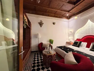 a bedroom with a bed and two chairs in it at Riad Fes Bab Sahra Palace in Fès
