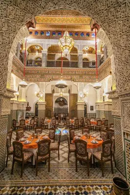 a dining room with tables and chairs in a building at Riad Fes Bab Sahra Palace in Fès