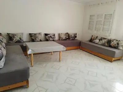 a living room with two beds and a table at Villa spacieuse 3 chambres à l'entrée de la ville in Imouzzer Kandar