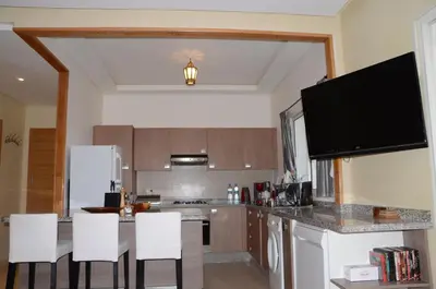a kitchen with a counter with white chairs in it at Apartment with large terrace and pool in Fès