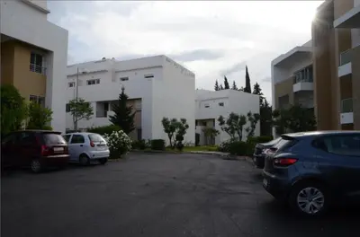 a parking lot with cars parked in front of a building at Apartment with large terrace and pool in Fès