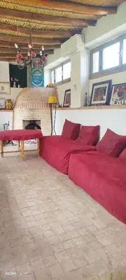 a large room with two red beds and a fireplace at Maison des maitres in Tafza