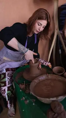 a woman making a pot on a pottery wheel at Maison des maitres in Tafza