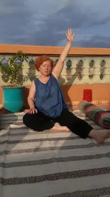 a woman sitting on the stairs with her arm in the air at Maison des maitres in Tafza