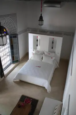 a bedroom with a bed with white sheets and pillows at Riad Yamcha in Meknès