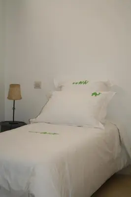 a white bed with green plants on the pillows at Riad Yamcha in Meknès
