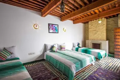 a bedroom with two beds and a fireplace at Dar Miouda Fes in Fès