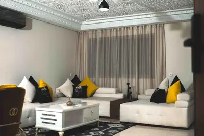 a living room with white couches and yellow pillows at Appart Hôtel Golden Sky Home in Beni Mellal