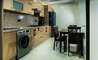 a kitchen with a washing machine and a table with chairs at Appart Hôtel Golden Sky Home in Beni Mellal
