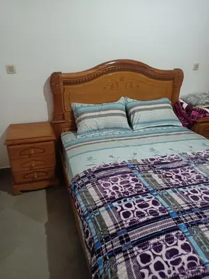 a bed with a wooden headboard and a night stand at Villa en montage in Khenifra