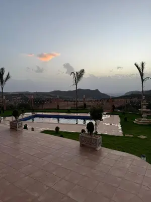 a view of a pool with palm trees and a city at Villa en montage in Khenifra