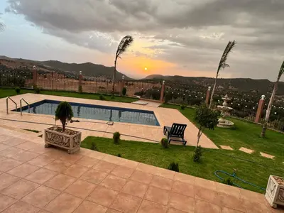 a view of a resort with a pool and palm trees at Villa en montage in Khenifra