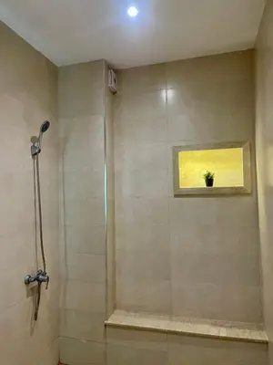 a bathroom with a shower with a plant in a window at Nura Apartment - Family only in Oulad Akkou