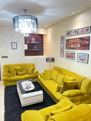 a living room with yellow couches and a chandelier at Aicha alaoui ismaili in Fès