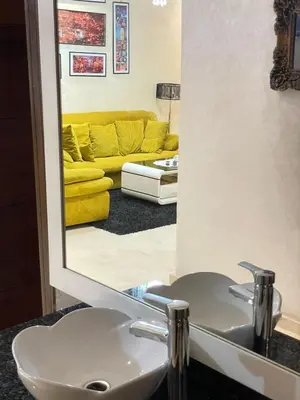 a bathroom mirror with a sink and a yellow couch at Aicha alaoui ismaili in Fès