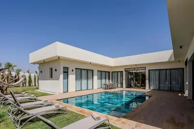 a villa with a swimming pool and chairs at Villa Famililale Shanya in Marrakech