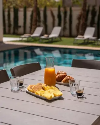 a table with a plate of bread and orange juice at Villa Famililale Shanya in Marrakech