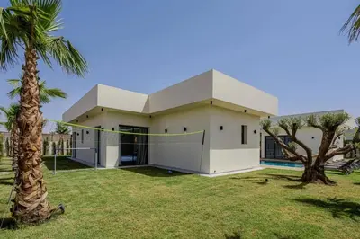 a white house with a palm tree in front of it at Villa Famililale Shanya in Marrakech