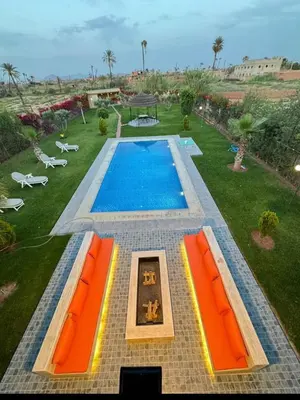 an overhead view of a swimming pool with orange furniture at villa Folki in Oulad Zbir