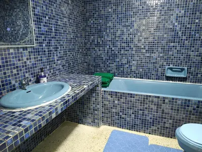 a blue tiled bathroom with a sink and a toilet at Spacious Apartment in the heart of downtown Fez in Fès
