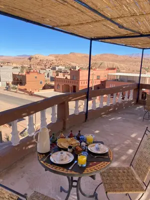 a table on a balcony with a view of a city at La Belle Vue Guest House in Aït Ben Haddou