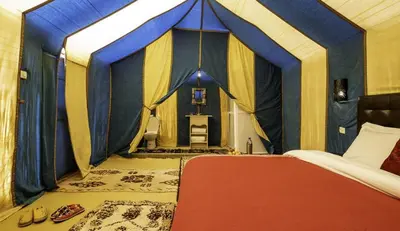 a bedroom with a blue and yellow tent at enjoy best night in desert merzouga in Merzouga