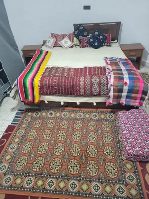 a bedroom with a bed with a rug on it at Yamna Cozy Cave in Bhalil